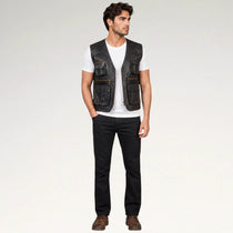A man modeling a black leather utility vest with multiple front pockets, worn over a white t-shirt and black jeans, standing against a light gray studio background.