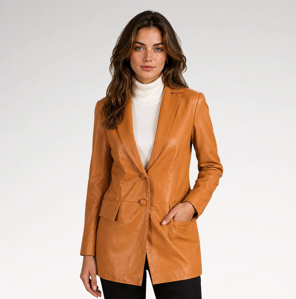 A woman modeling a tan faux-leather blazer over a white turtleneck sweater and black pants, photographed against a light gray studio background.