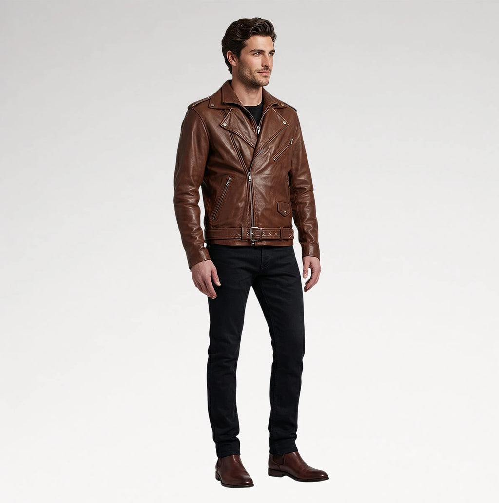 A man modeling a brown leather moto jacket, paired with black jeans and brown boots, standing against a light gray studio background.