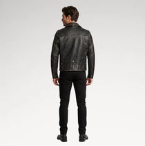 A man viewed from the back wearing a black leather jacket, black slim-fit jeans, and black shoes, standing against a light gray studio background.