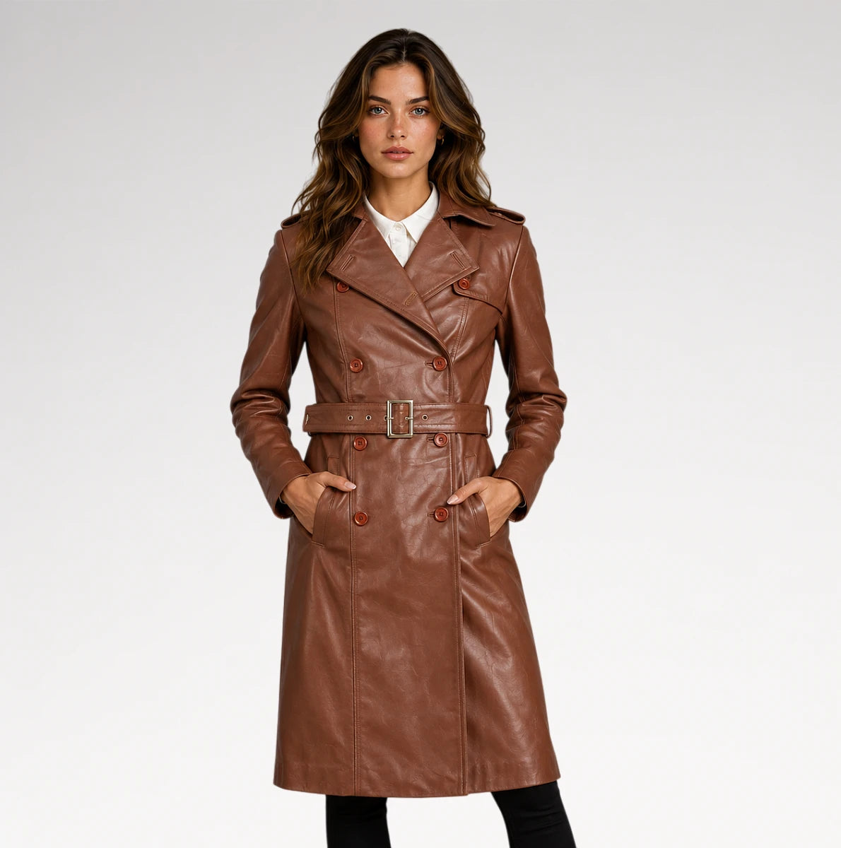 A woman modeling a brown faux-leather double-breasted trench coat with a matching belt, worn over a white collared shirt and black pants, against a light gray studio background. Main image