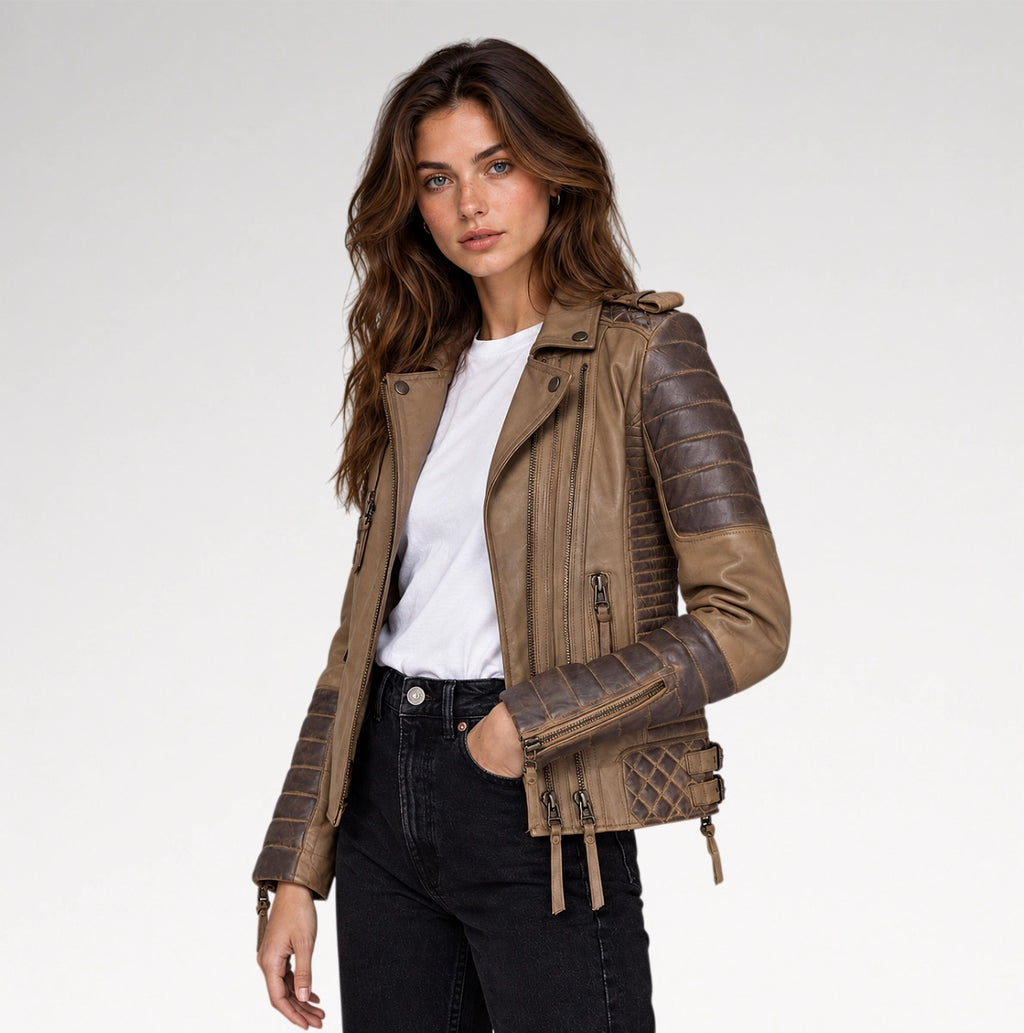 A woman modeling a brown faux leather moto jacket with quilted and textured sleeve panels, worn over a white t-shirt and black jeans, against a light gray studio background.