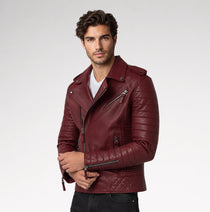 A man viewed from the back wearing a black leather biker jacket with quilted paneling and gold-tone zipper details on a light gray studio background.