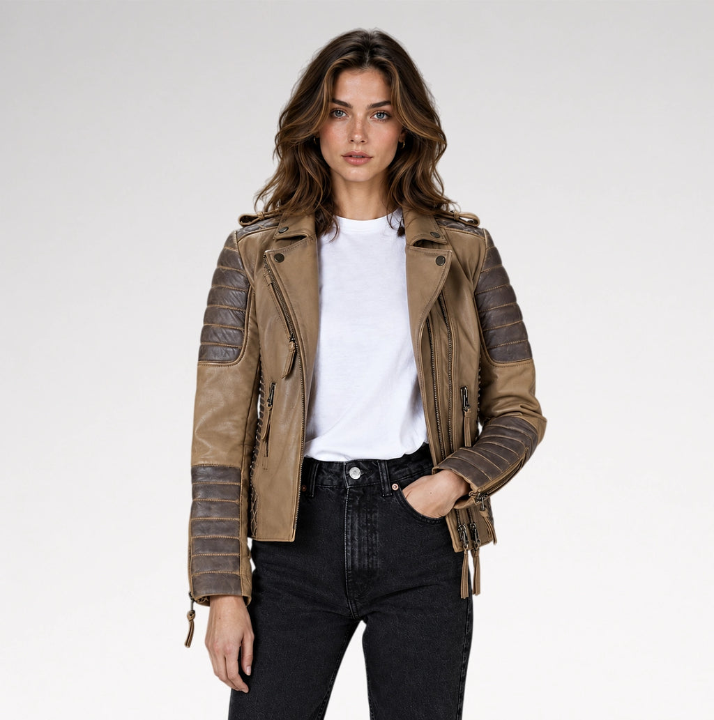 A woman modeling a brown faux leather moto jacket with textured ribbed sleeves, worn over a white t-shirt and black jeans, against a light gray studio background.