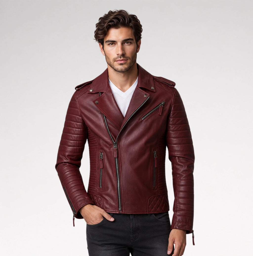 A man wearing a burgundy leather moto jacket over a white t-shirt and black jeans, standing against a light gray studio background.