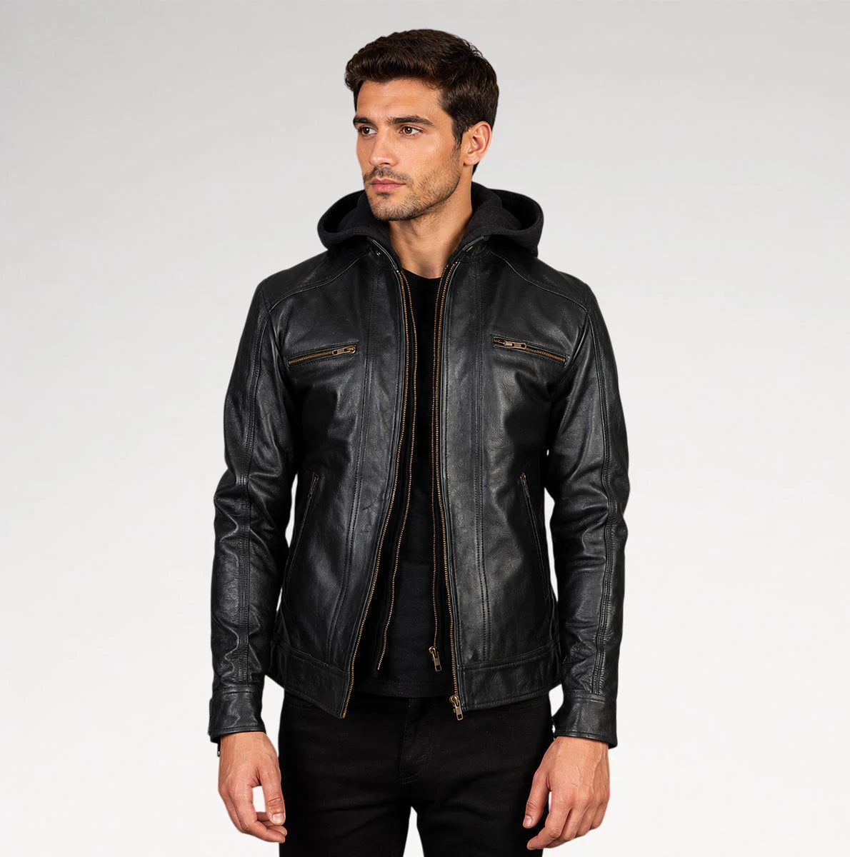 A man wearing a black leather hooded jacket with gold-tone zippers, photographed against a light gray studio background.