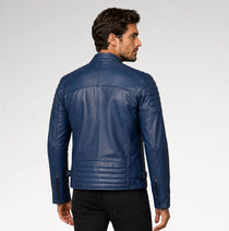 A man wearing a dark blue leather biker jacket, shown from the back and side profile against a light gray studio background.