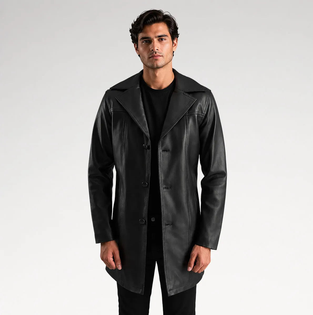 A man modeling a black leather trench coat over a black shirt and trousers, standing against a light gray studio background. Main image