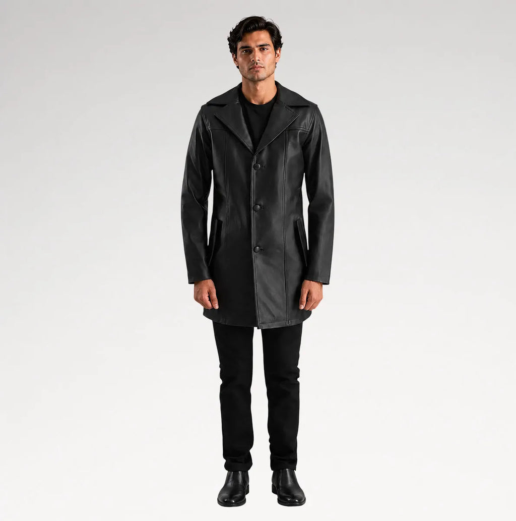 A man modeling a black leather-like coat over a black outfit, standing against a light gray studio background.