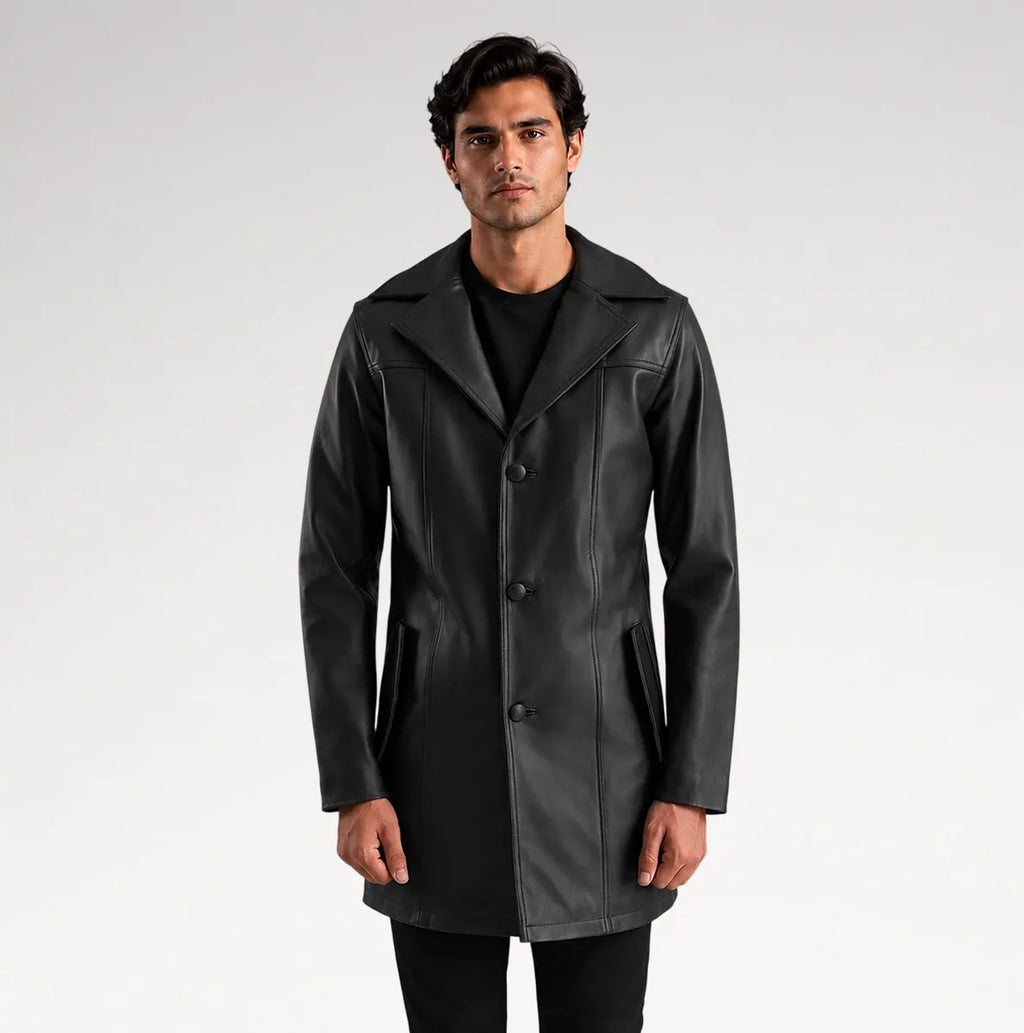 A man modeling a black leather-like coat over a black outfit, standing against a light gray studio background.