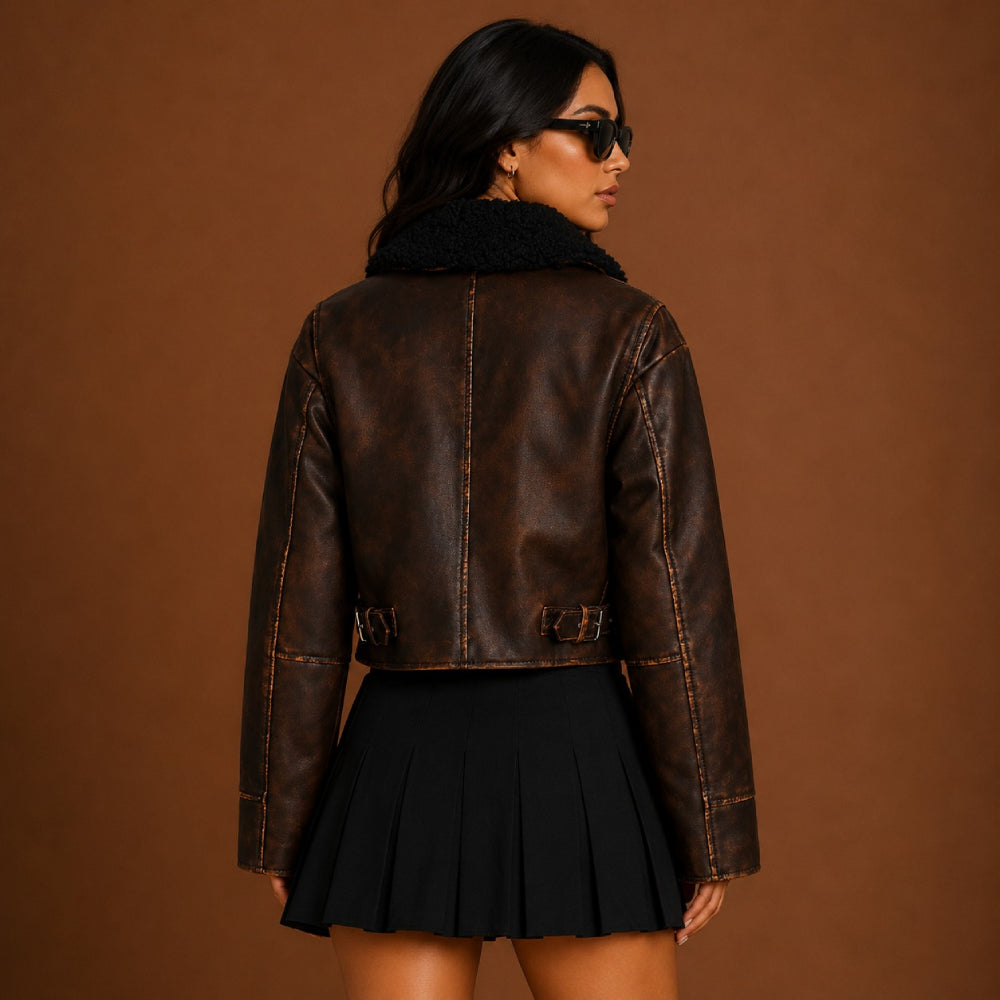 Woman wearing a brown leather jacket and black skirt against a brown background