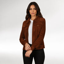 A woman modeling a brown suede jacket over a white t-shirt and black pants, photographed against a light gray studio background.