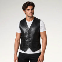 A man modeling a black leather vest over a white t-shirt and black pants, photographed against a light gray studio background.