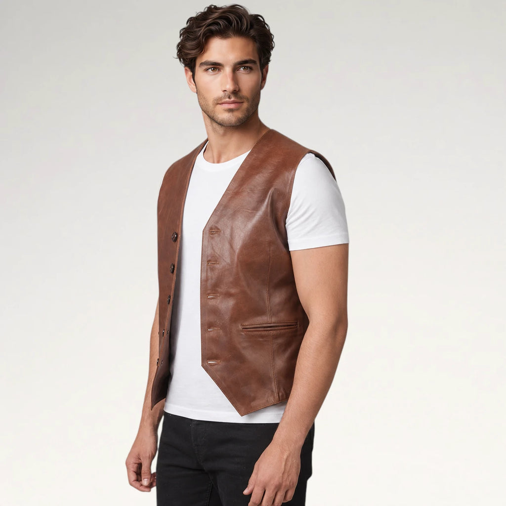 A man wearing a brown leather vest over a white t-shirt and black pants, photographed against a light gray studio background.