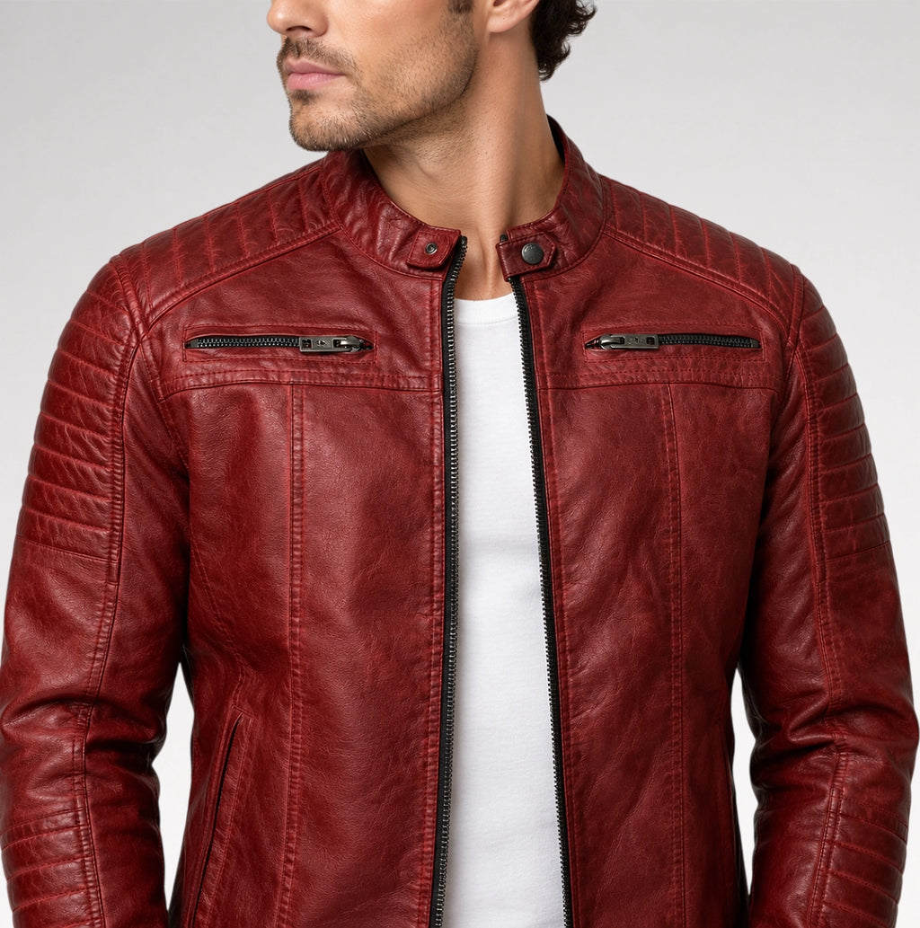 A man wearing a textured red leather jacket with a stand collar, black front zipper, and zippered chest pockets over a white t-shirt, photographed against a light gray studio background.