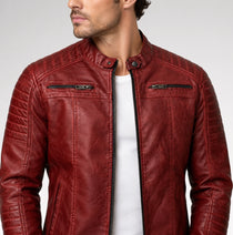 A man wearing a textured red leather jacket with a stand collar, black front zipper, and zippered chest pockets over a white t-shirt, photographed against a light gray studio background.