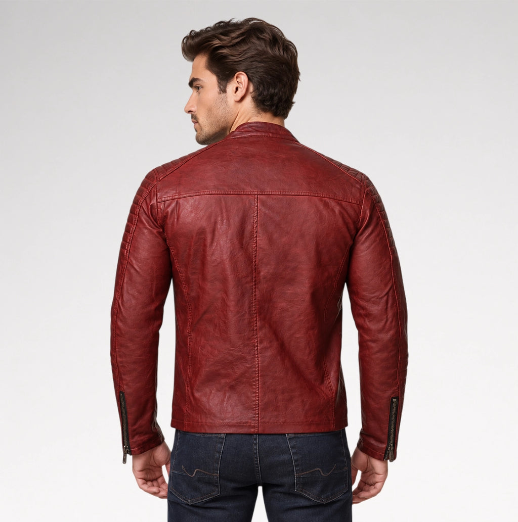 A man viewed from the back wearing a distressed red leather jacket and dark blue jeans, standing against a light gray studio background.