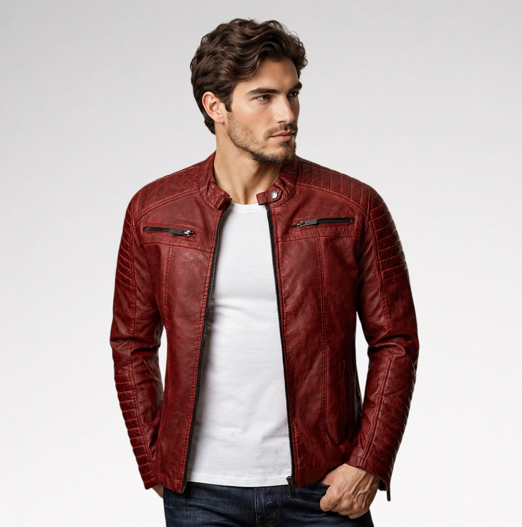 A man wearing a textured, quilted burgundy leather jacket over a white t-shirt and dark jeans, photographed against a clean light gray studio background.