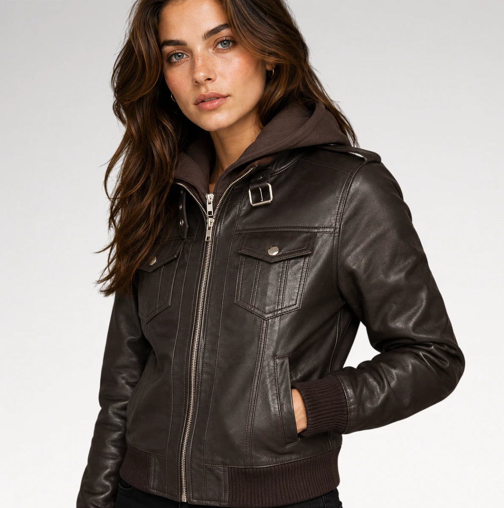 A woman wearing a dark brown faux-leather hooded jacket with a front zipper, chest flap pockets, and ribbed cuffs and hem, photographed against a light gray studio background.