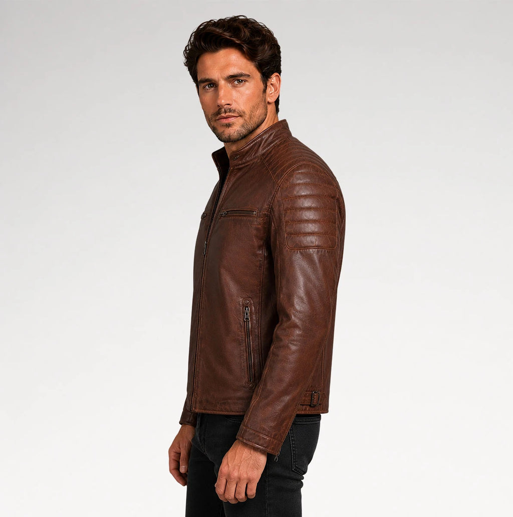 A man wearing a brown leather jacket, shown in profile against a light gray studio background.