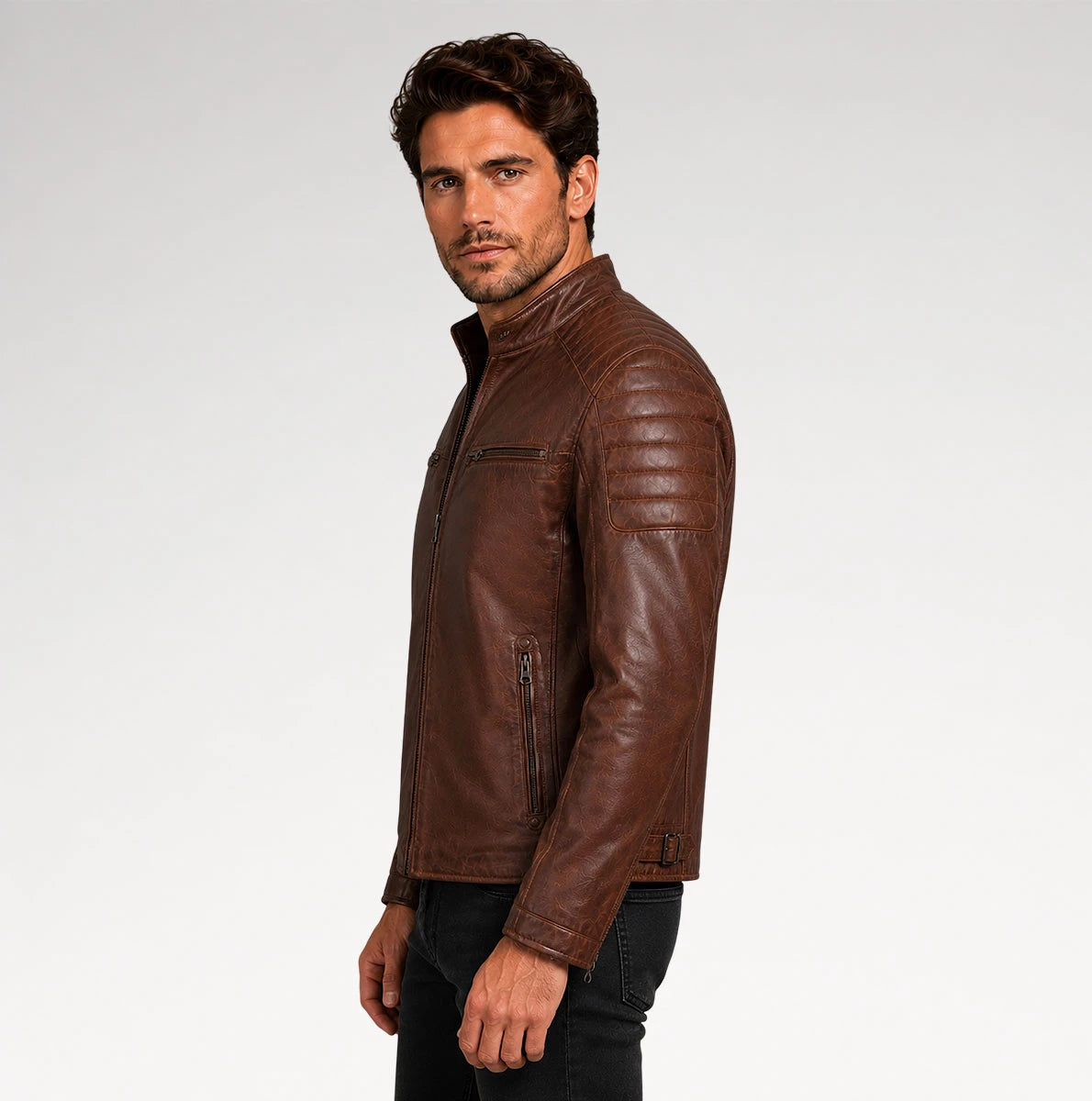 A man wearing a brown leather jacket, shown in profile against a light gray studio background.