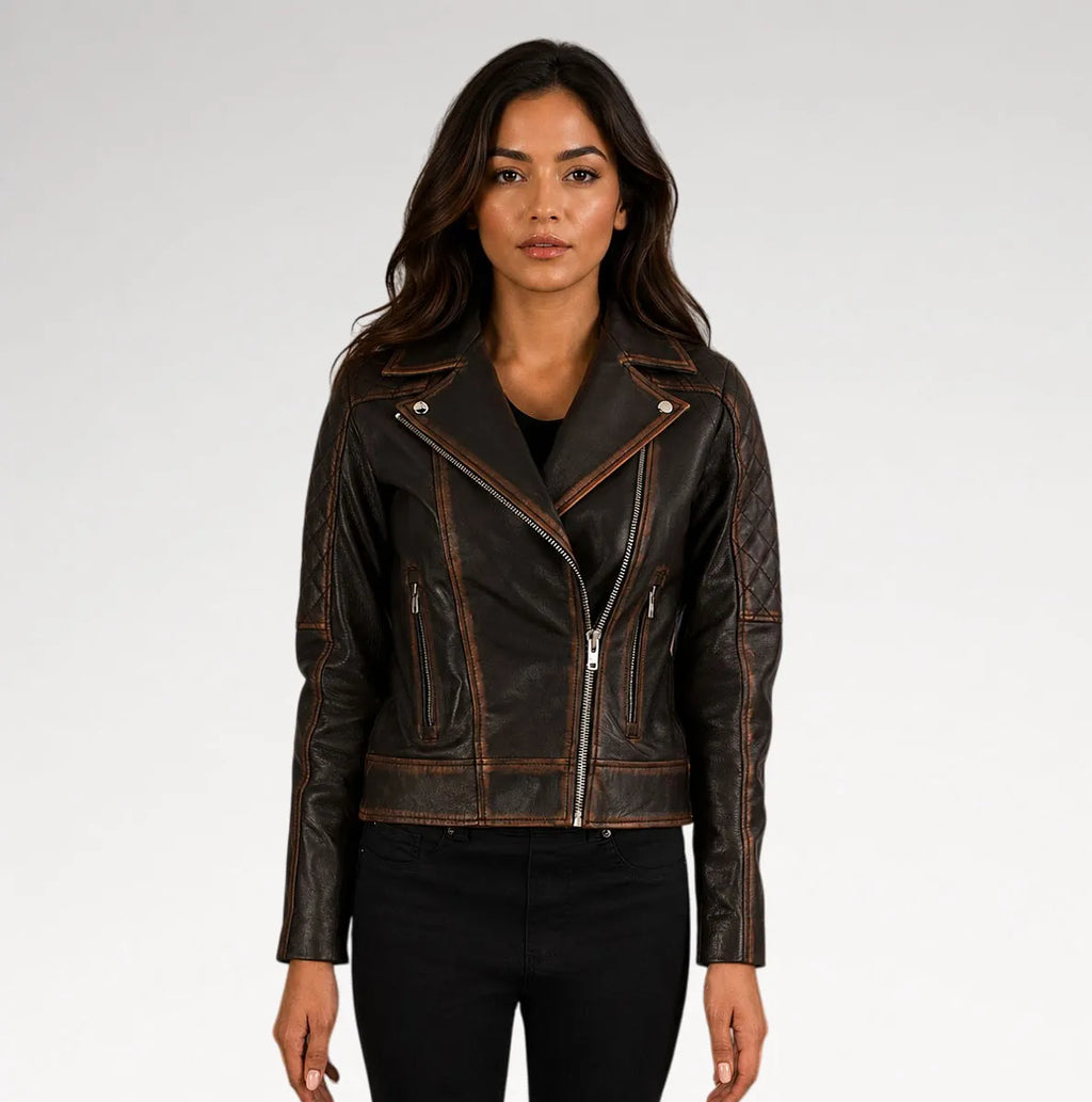 A woman modeling a dark brown distressed leather moto jacket with silver zippers and contrast stitching, paired with black pants against a light gray studio background.