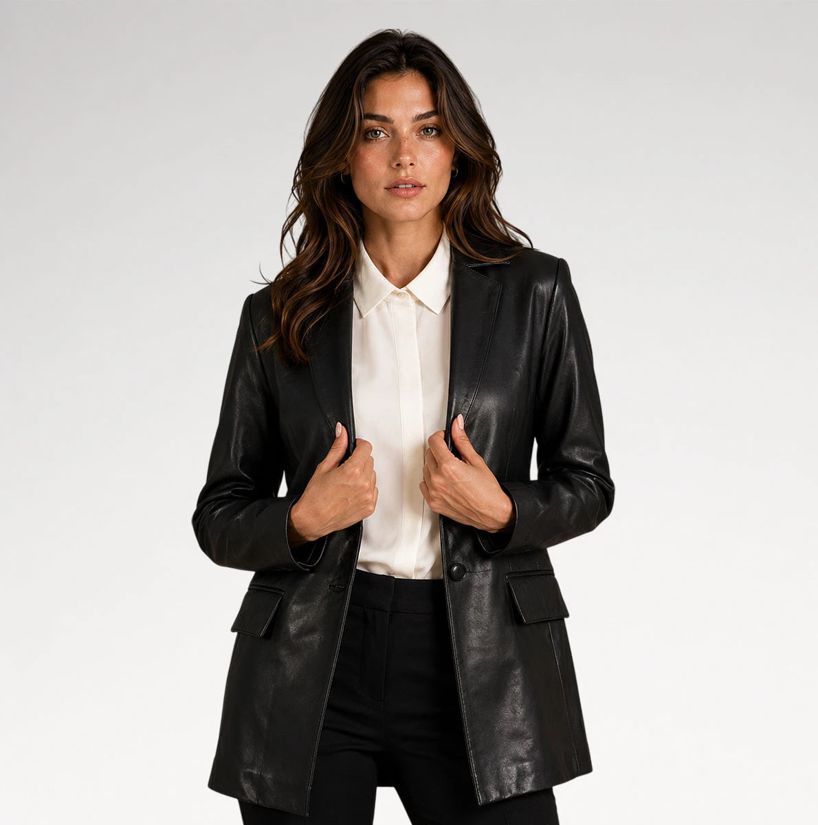 A woman modeling a black faux-leather blazer over a white collared shirt and black trousers, photographed against a light gray studio background. Main image