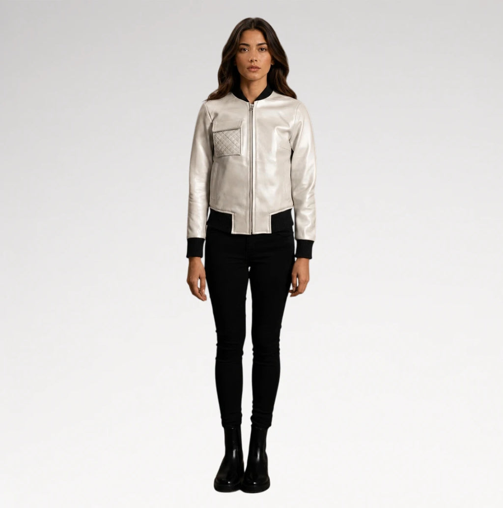 A woman modeling a shiny silver bomber jacket with black trim, paired with black skinny pants and black boots, against a light gray studio background.