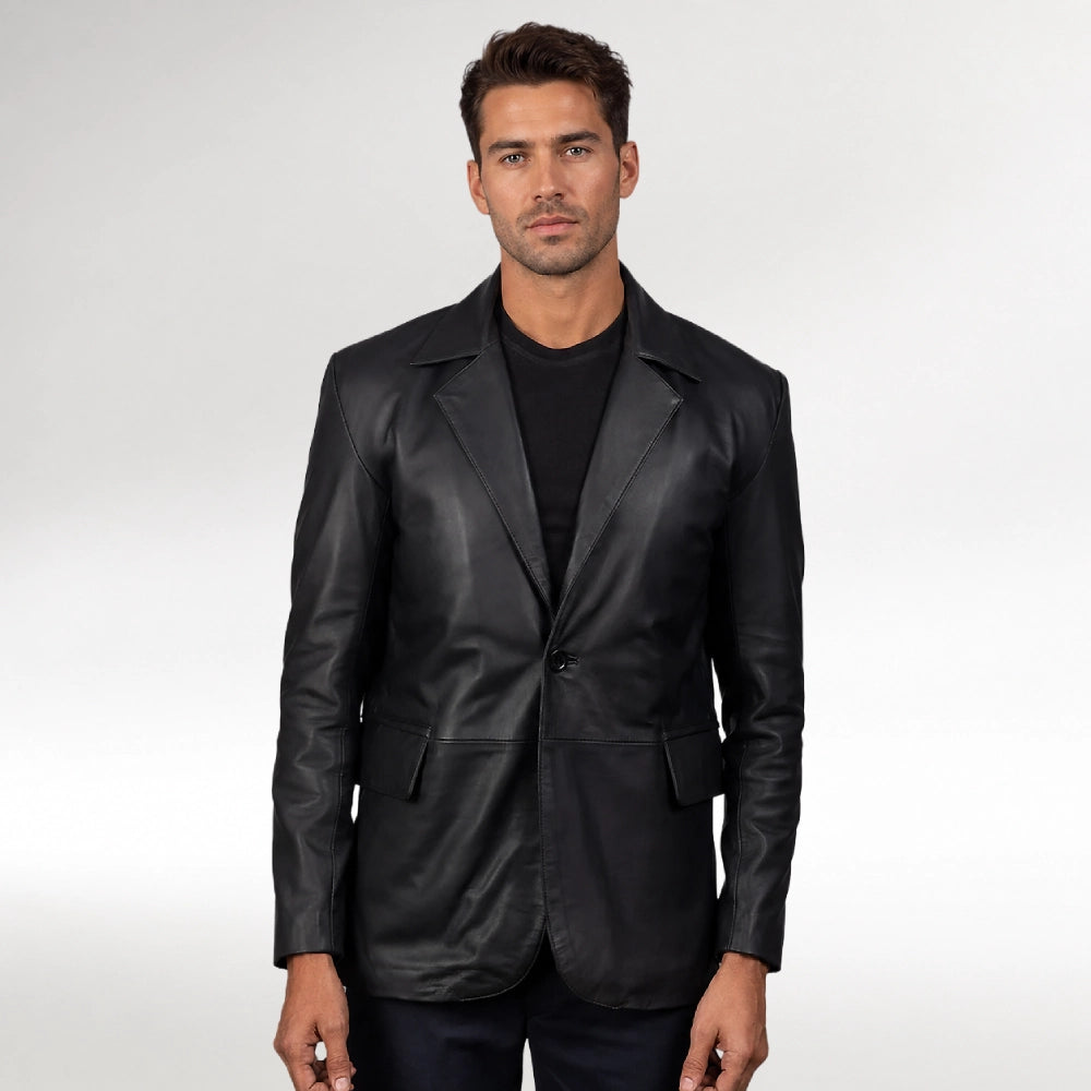 A man wearing a black leather blazer over a black t-shirt, standing against a light gray studio background.