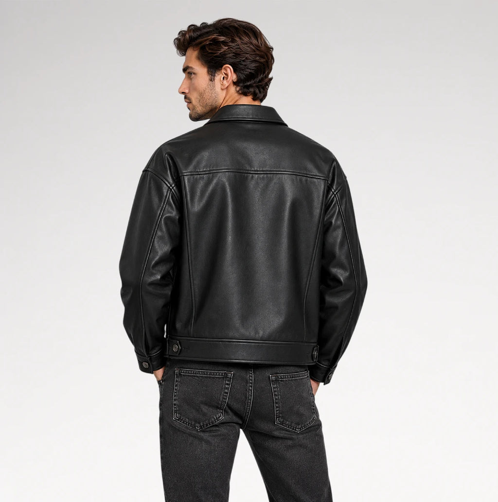 A man wearing a black leather jacket, shown from the back, paired with dark gray jeans against a light gray studio background.