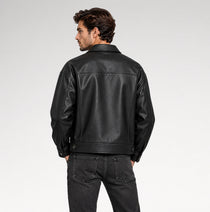 A man wearing a black leather jacket, shown from the back, paired with dark gray jeans against a light gray studio background.