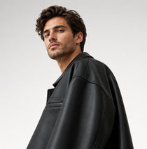 A man wearing a black leather jacket, photographed from a side profile against a light gray studio background.