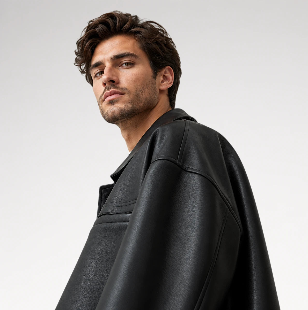 A man wearing a black leather jacket, photographed from a side profile against a light gray studio background.