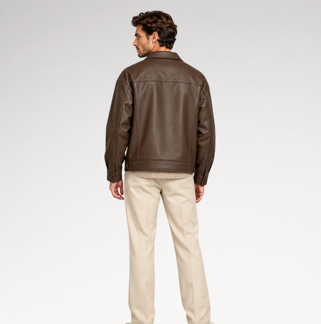 A man shown from the back wearing a dark brown leather jacket and beige trousers, standing against a light gray studio background.