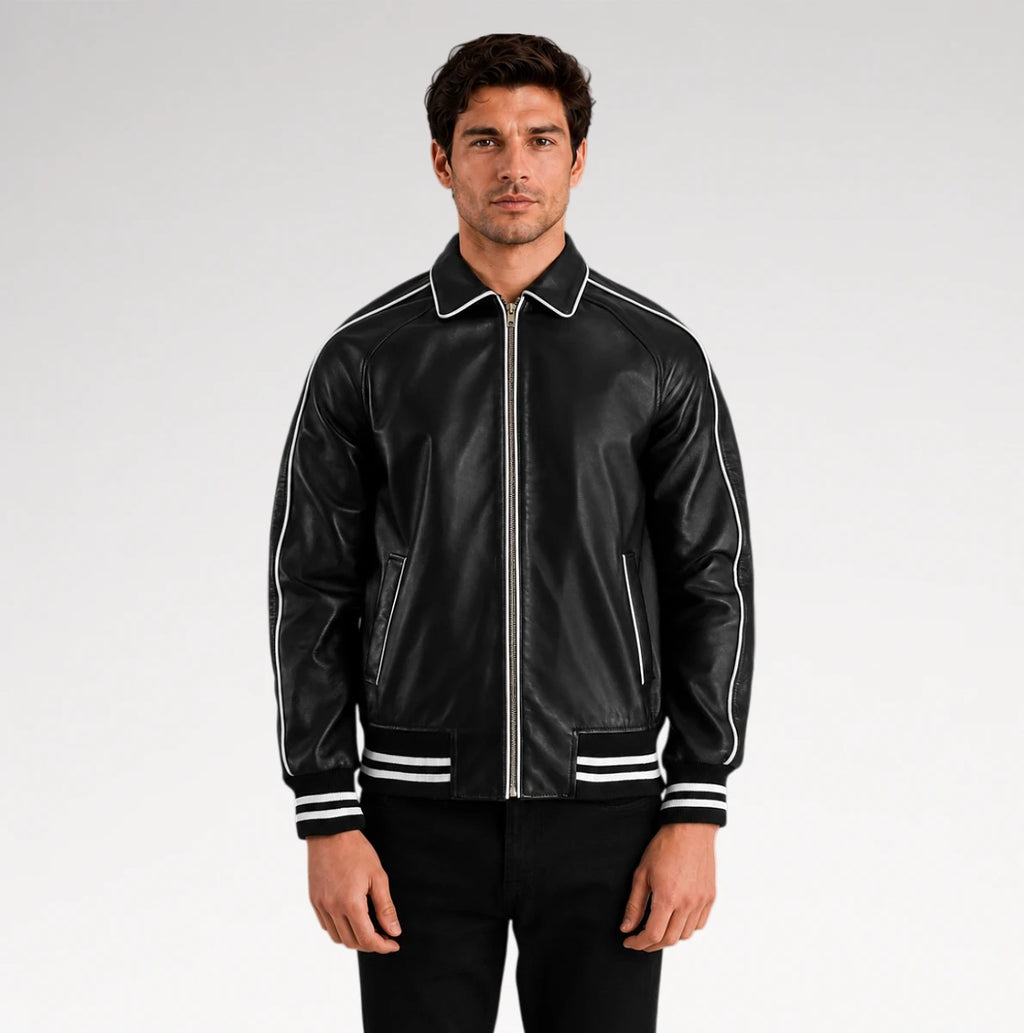 A man wearing a black leather bomber jacket with white contrast piping, a white collar, and white stripes on the cuffs and hem, paired with black pants against a light gray studio background.