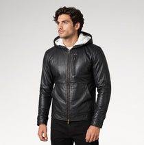A man wearing a black leather hooded jacket with a white hood lining, standing against a light gray studio background.