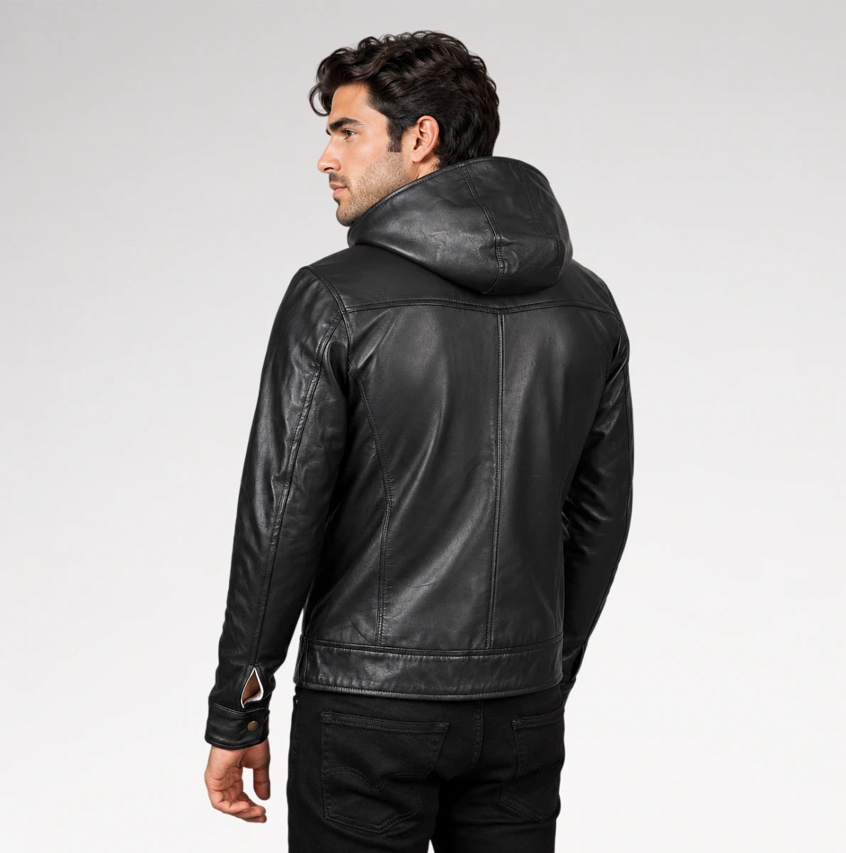 A man wearing a black leather hooded jacket, shown from a rear three-quarter angle against a light gray studio background.