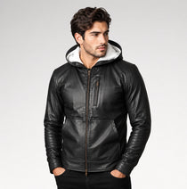A man wearing a black faux-leather hooded jacket with a white sherpa-lined hood, standing against a light gray studio background.
