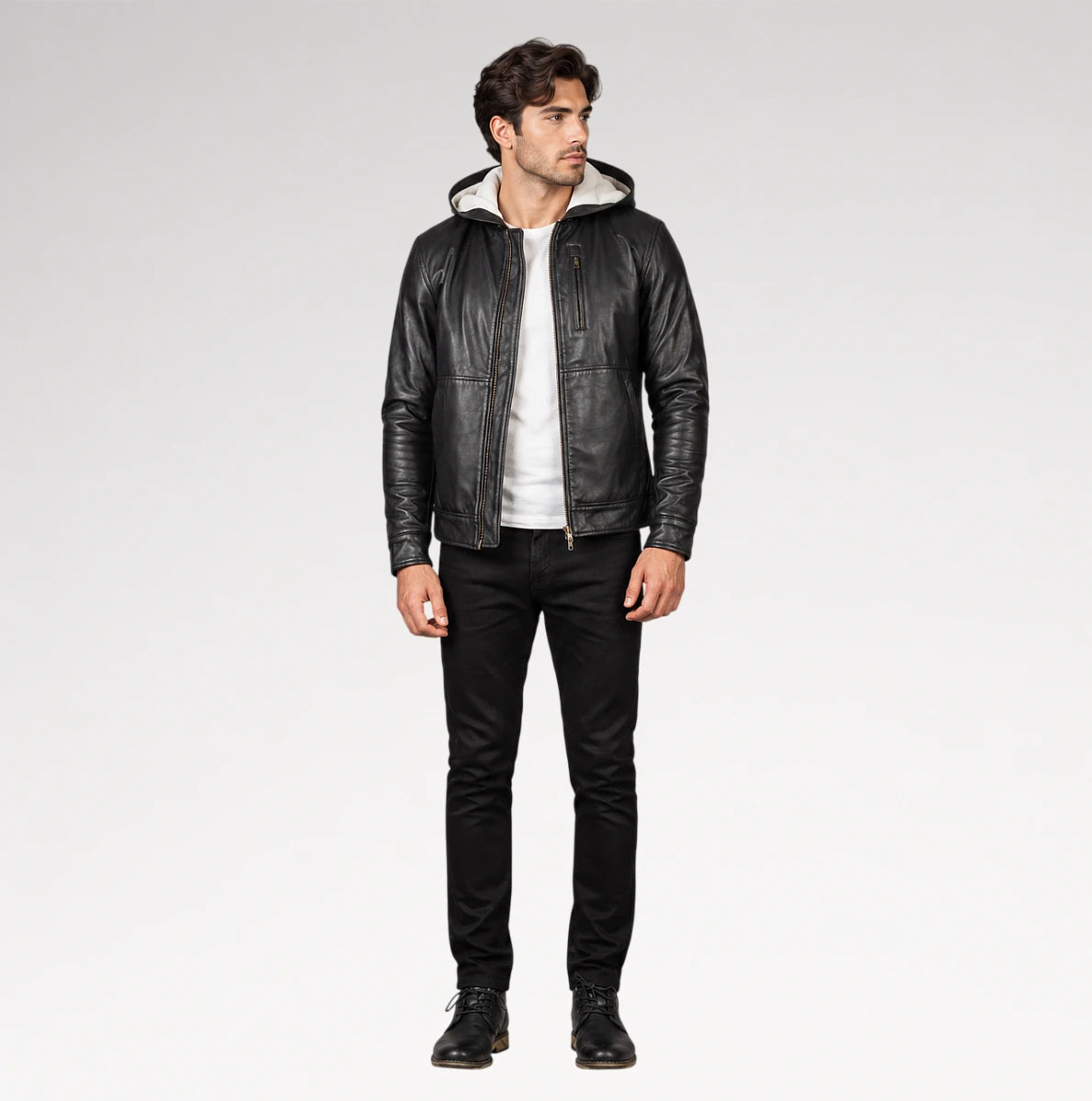 A man modeling a black leather hooded jacket with a light-colored lining, worn over a white t-shirt and black jeans, against a plain light gray studio background.