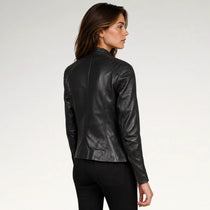 A woman wearing a black leather jacket, shown from a side-back angle against a plain light gray studio background.