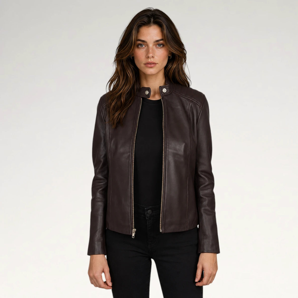 A woman modeling a dark brown leather jacket with a stand collar and front zipper, worn over a black top and black pants, against a plain light gray studio background. Main image