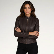 A woman modeling a dark brown leather moto jacket with a front zipper, set against a plain light gray studio background.