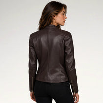 A woman shown from the back wearing a fitted dark brown faux-leather moto jacket with black jeans, photographed against a clean light gray studio background.