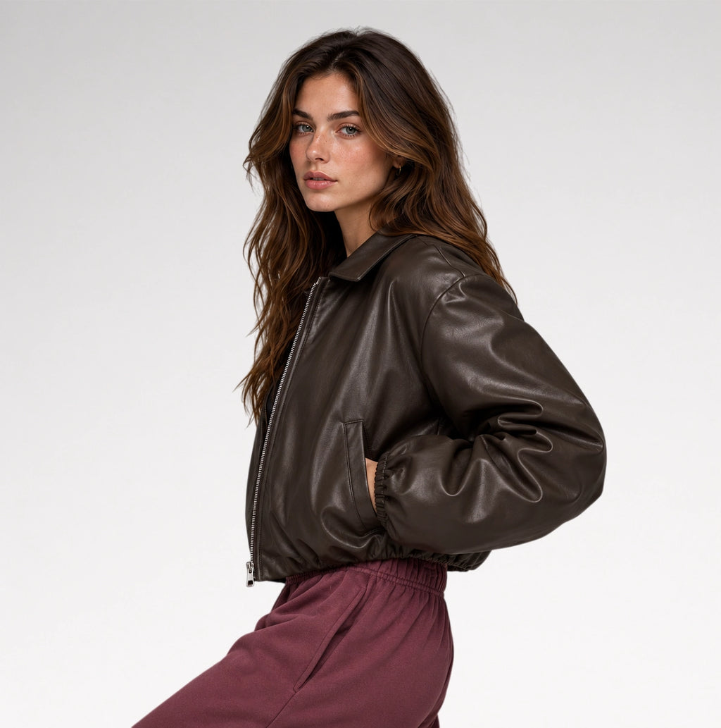 A woman wearing a dark brown faux-leather bomber jacket and burgundy sweatpants, photographed against a clean white studio background.