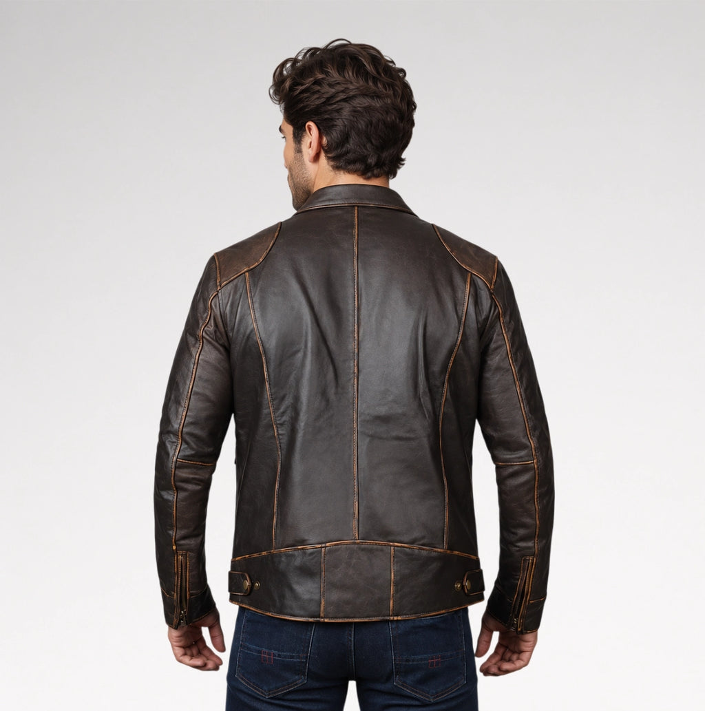 A man viewed from the back wearing a dark brown leather jacket with contrasting tan stitching, paired with dark blue jeans, against a light gray studio background.