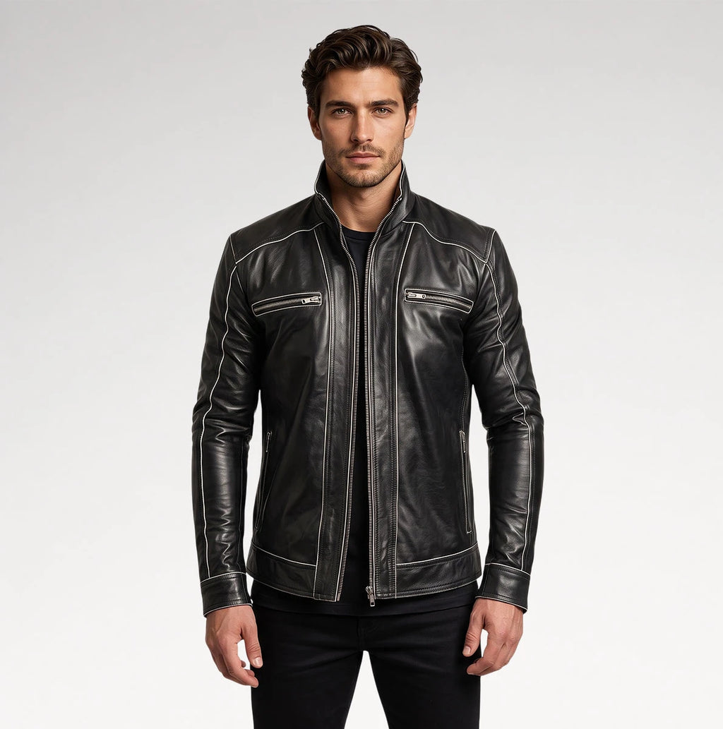 A man wearing a black leather jacket with contrasting white stitching and zippered chest pockets, photographed against a light gray studio background.
