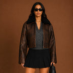 Woman wearing a brown leather jacket with black fur collar against a brown background