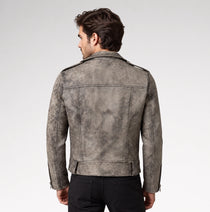 A man viewed from the back wearing a distressed gray leather jacket with shoulder epaulets and black pants, set against a plain light gray studio background.