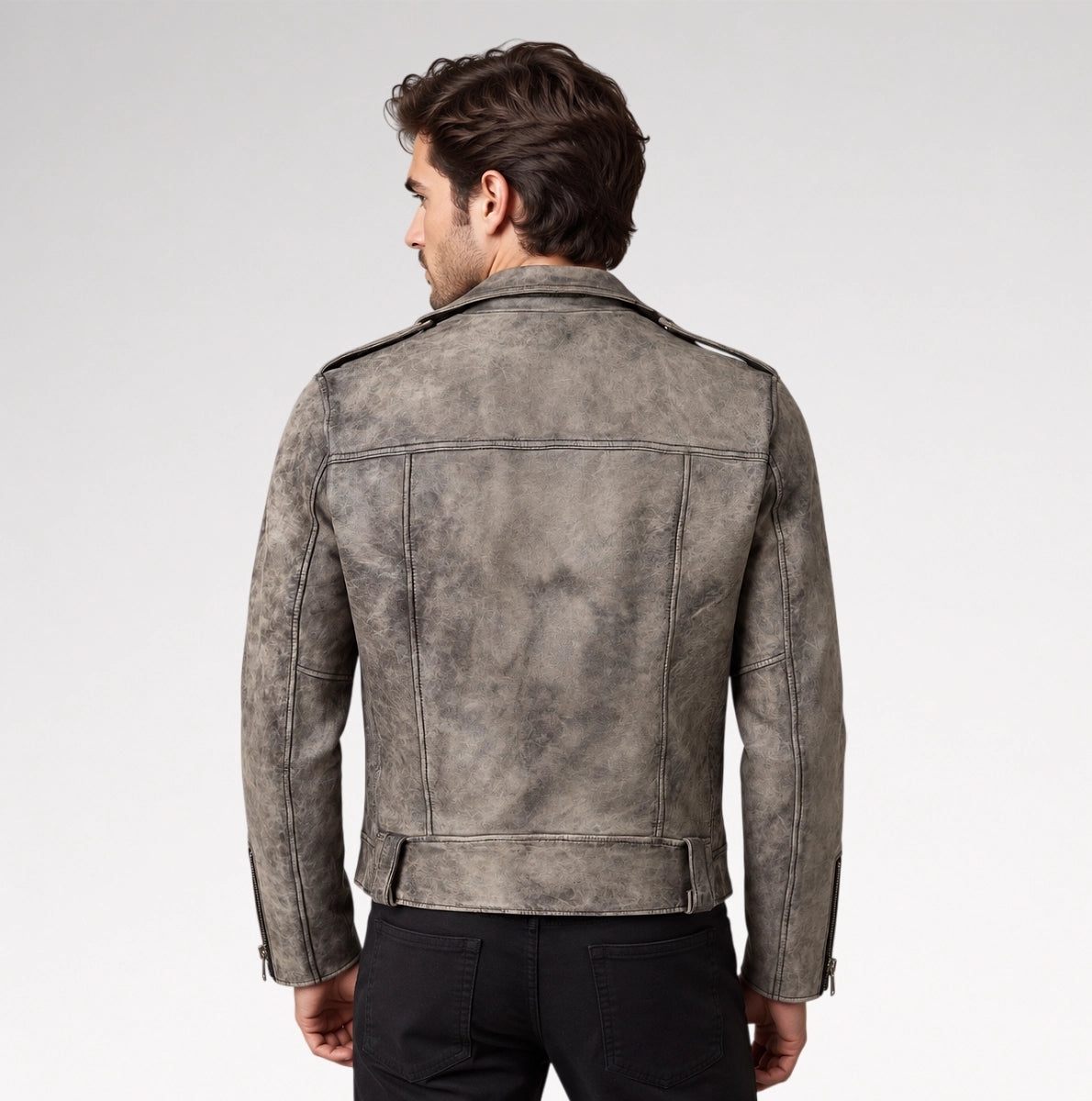 A man viewed from the back wearing a distressed gray leather jacket with shoulder epaulets and black pants, set against a plain light gray studio background.