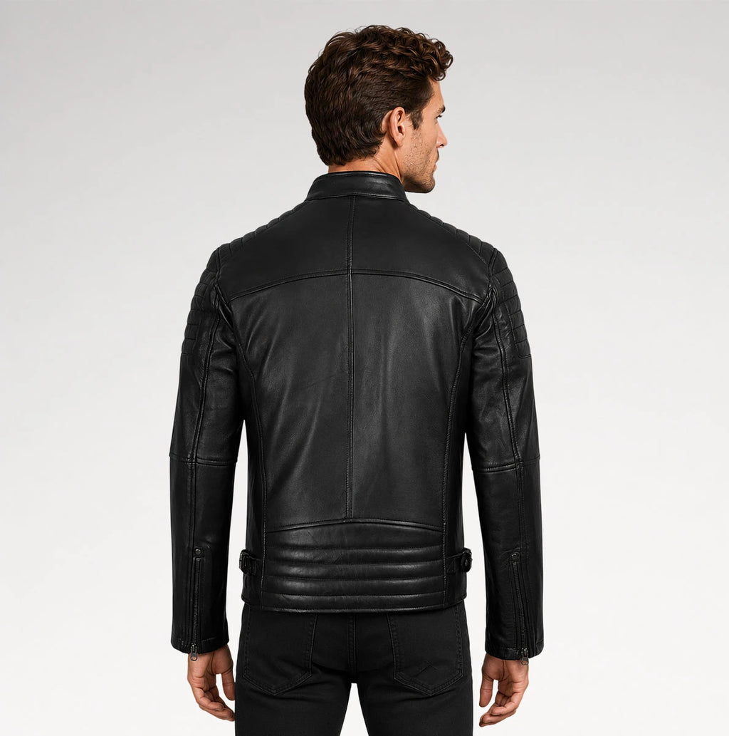 A man viewed from the back wearing a black leather biker jacket with quilted details at the waist and shoulders, set against a plain light gray studio background.